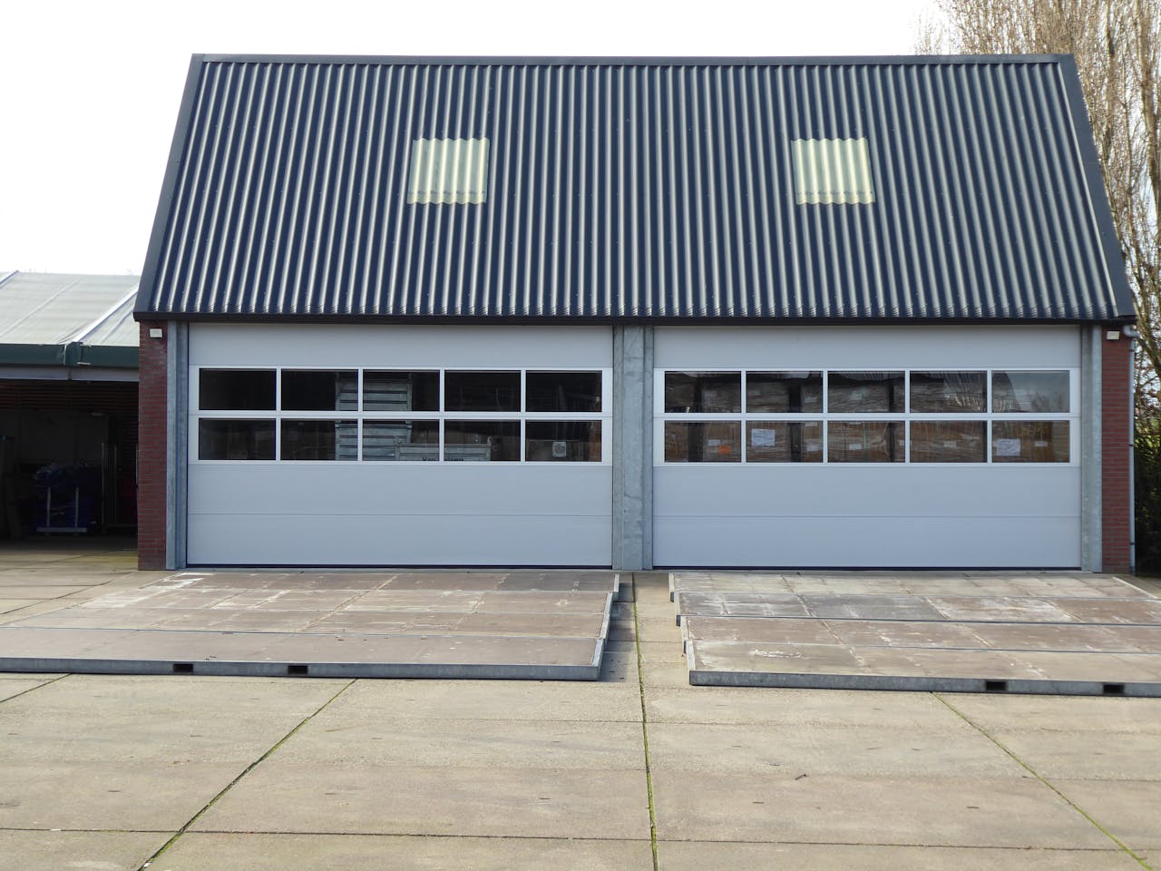 Front view of a modern warehouse building with corrugated roofing and skylights.